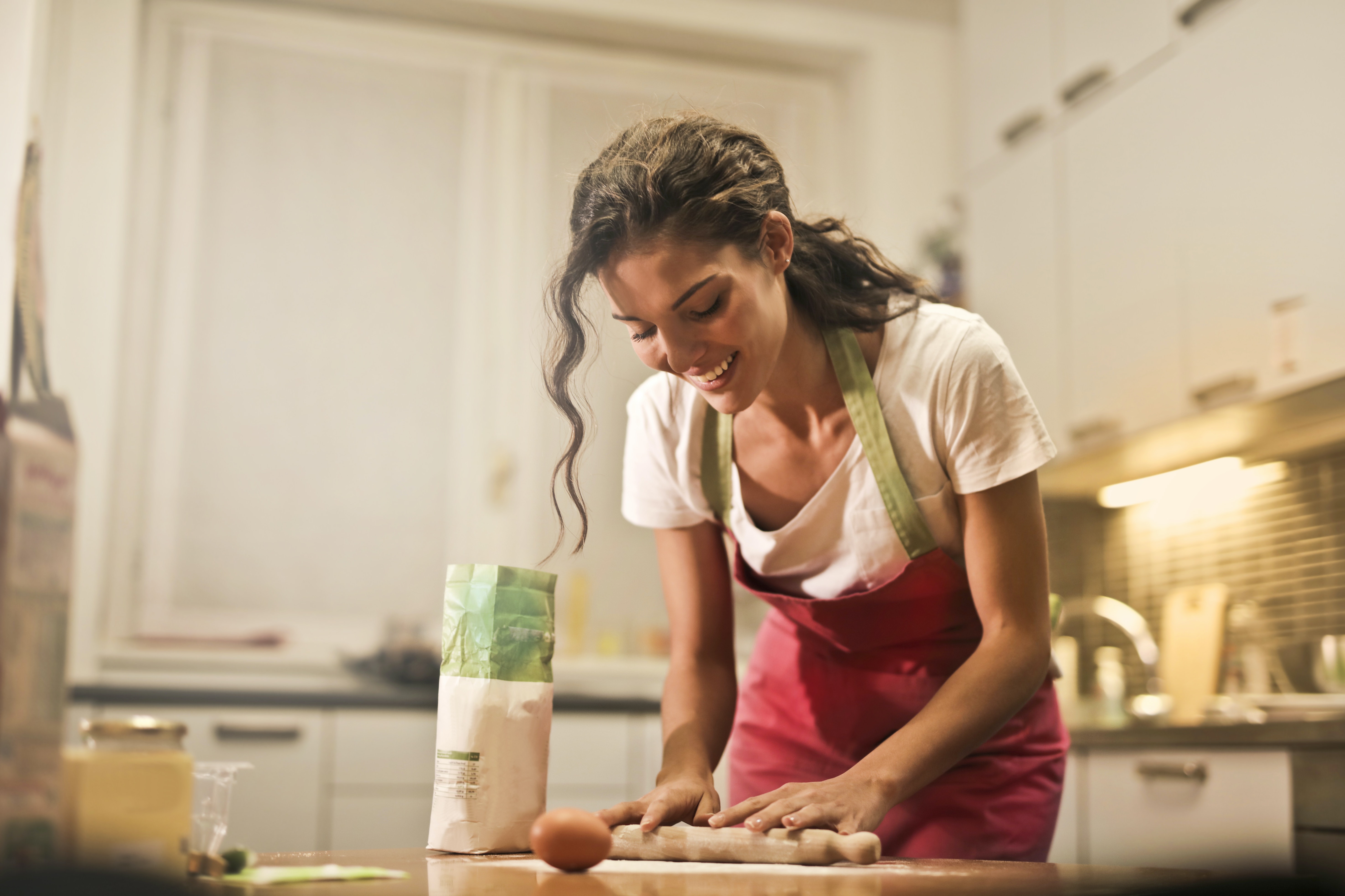 A woman in an apron cooking on a table in the kitchen. 