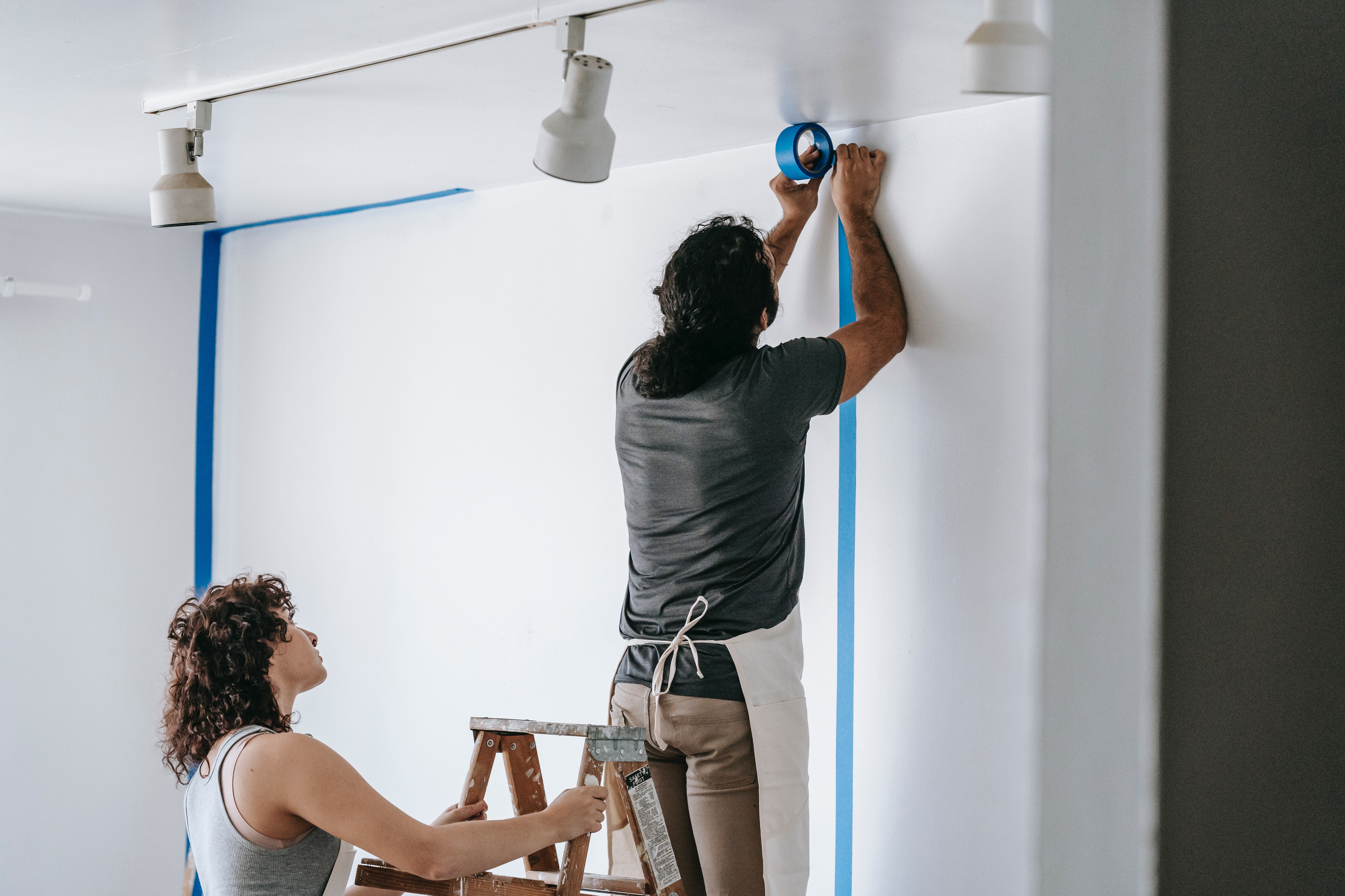 Two people prepping a room for paint.