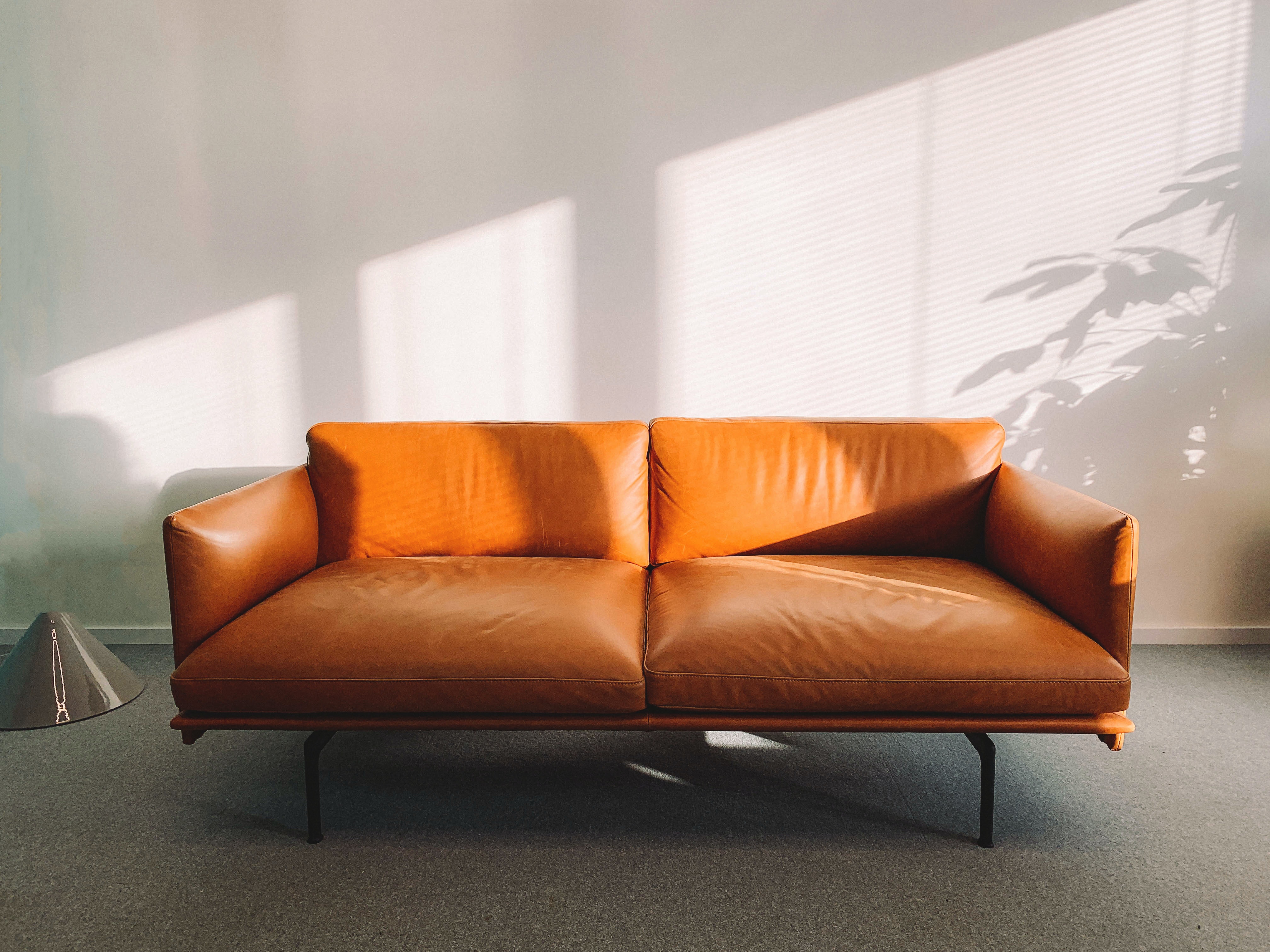 An orange leather couch in a white room. 