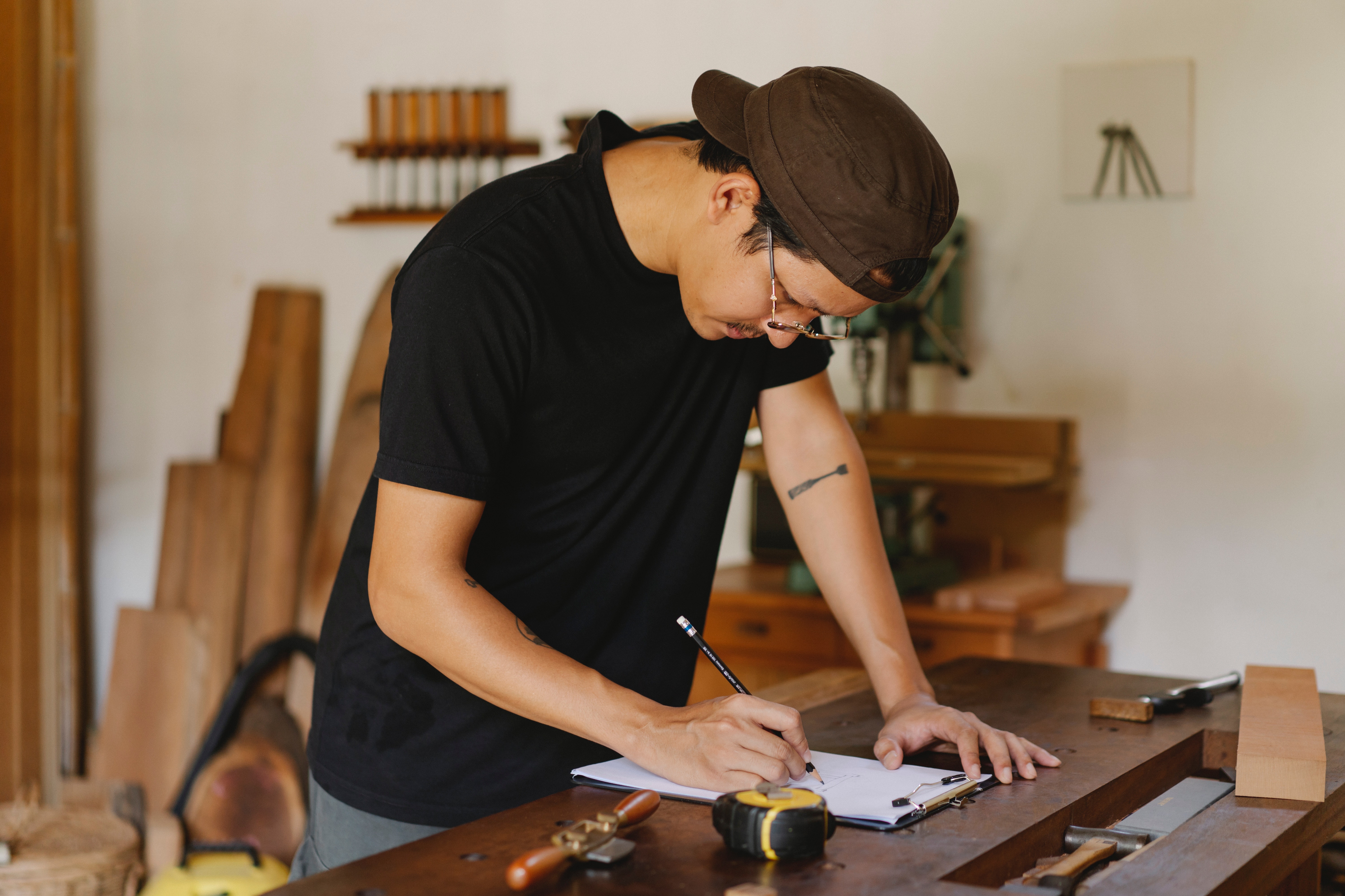 A man using pencil and paper for a woodworking project. 