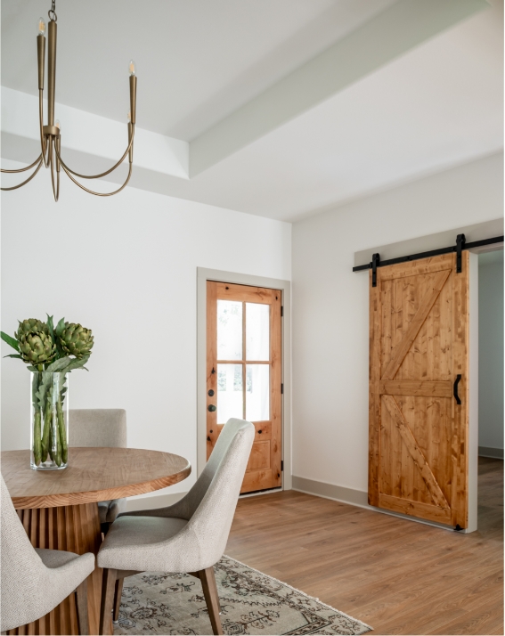 Table and chairs in the entryway of a home with a wooden door.