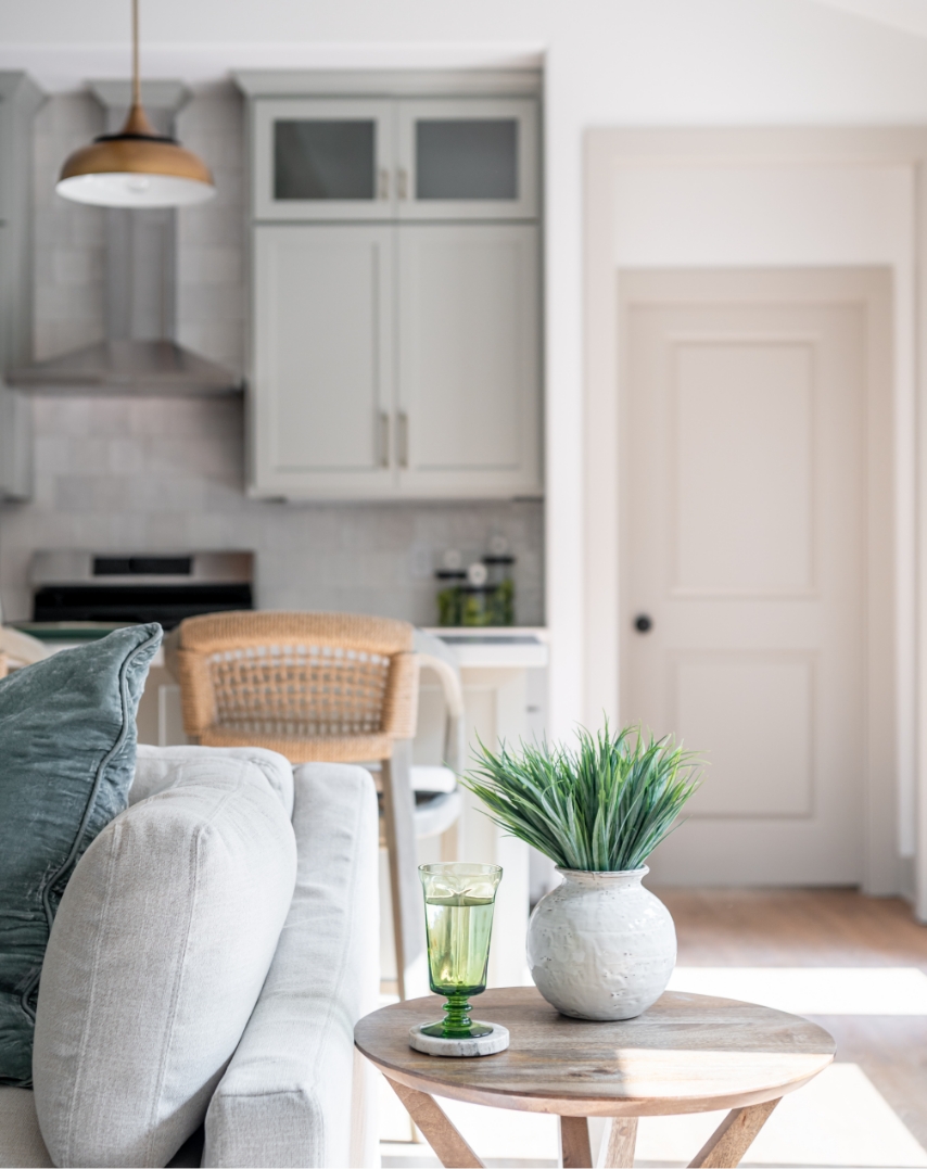 A couch with pillows and a kitchen with barstools