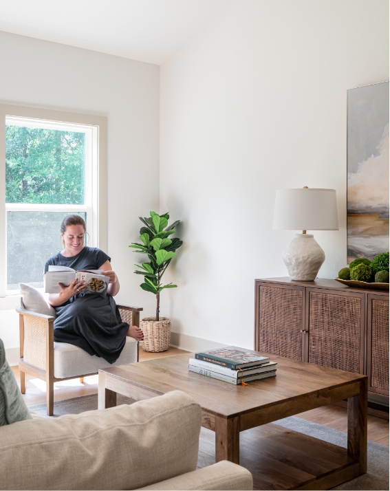 A woman reading a book in a living room.