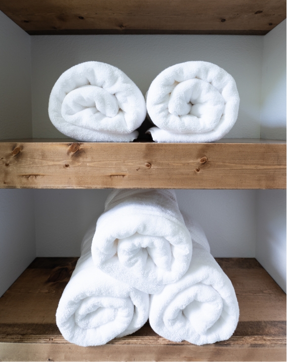 Rolled-up bath towels on wooden shelves