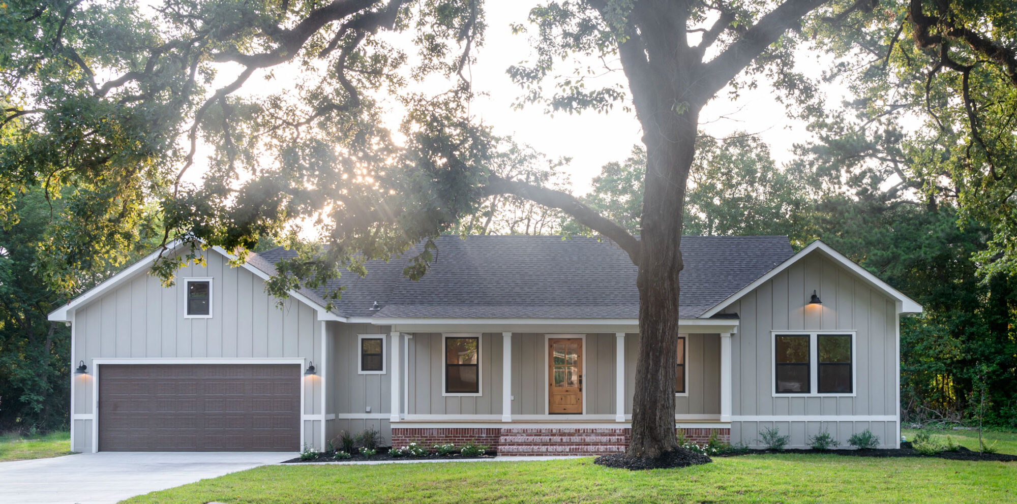 A custom-built home with a tree in the front yard.