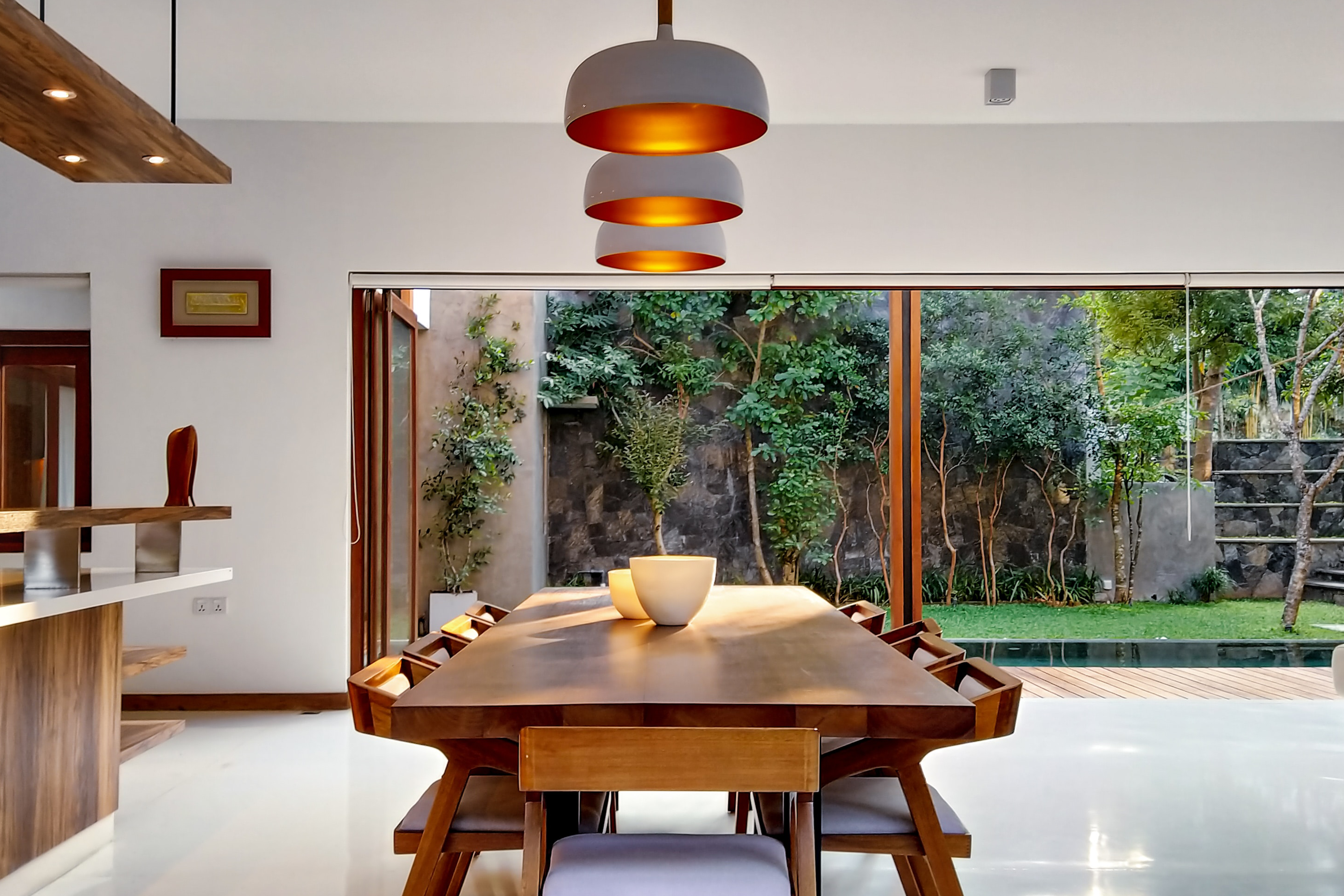 A dining room table with large windows and overhead lighting.