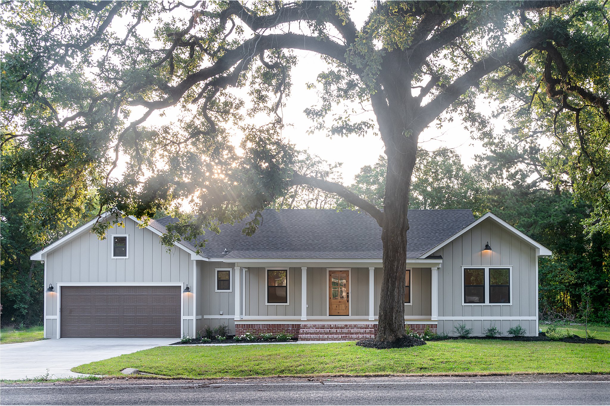 A custom-built home with a tree in the front yard.