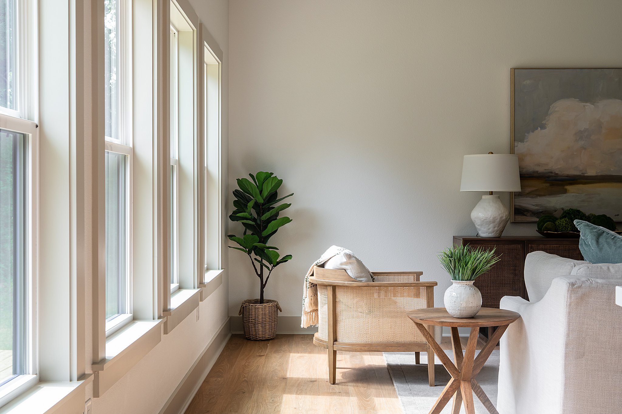 A living room with chairs, couches, plants and a lamp