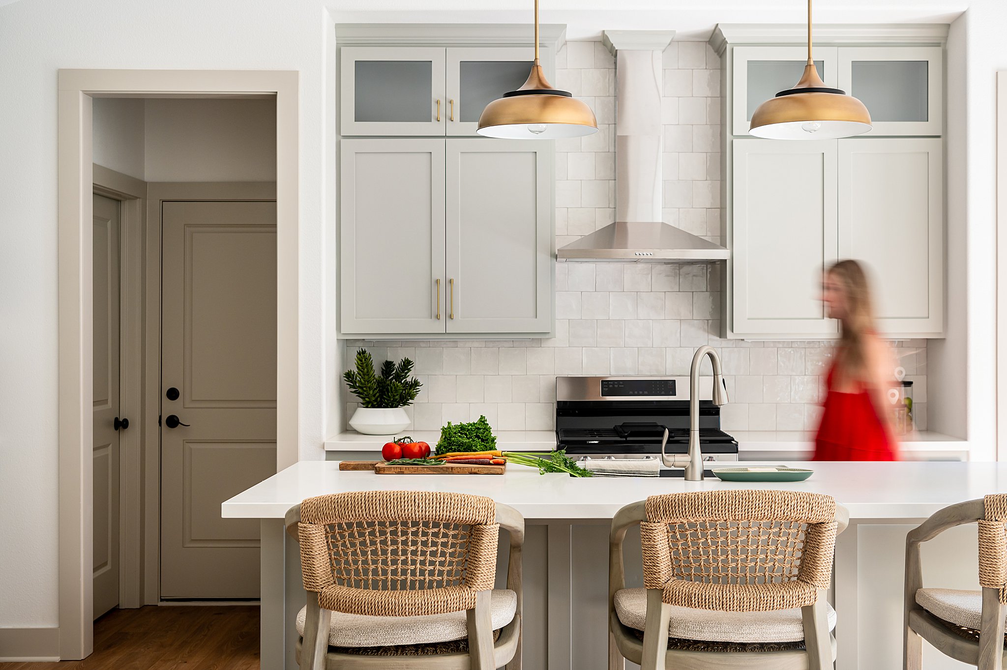 A woman walking in a white kitchen. 