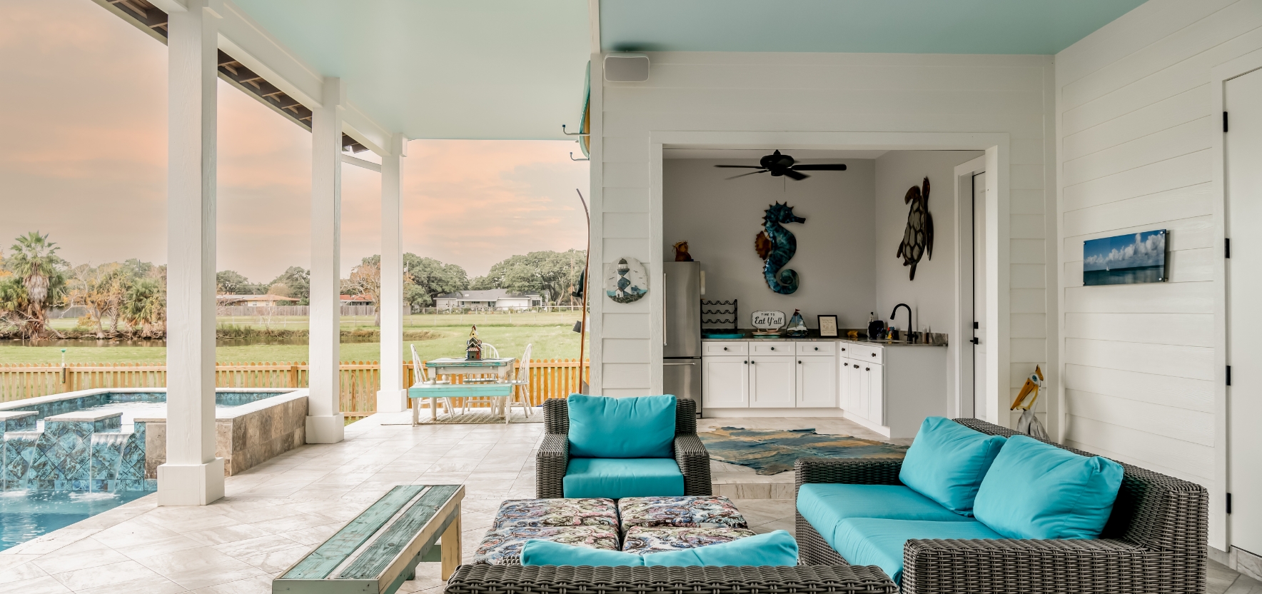 A couch with pillows in front of a kitchen with chairs.