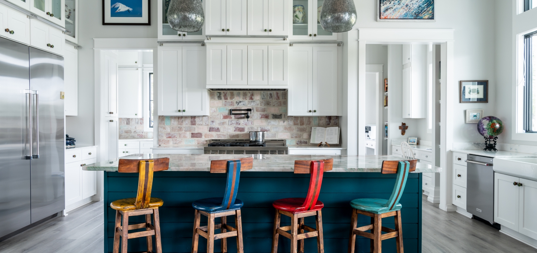 A couch with pillows in front of a kitchen with chairs.