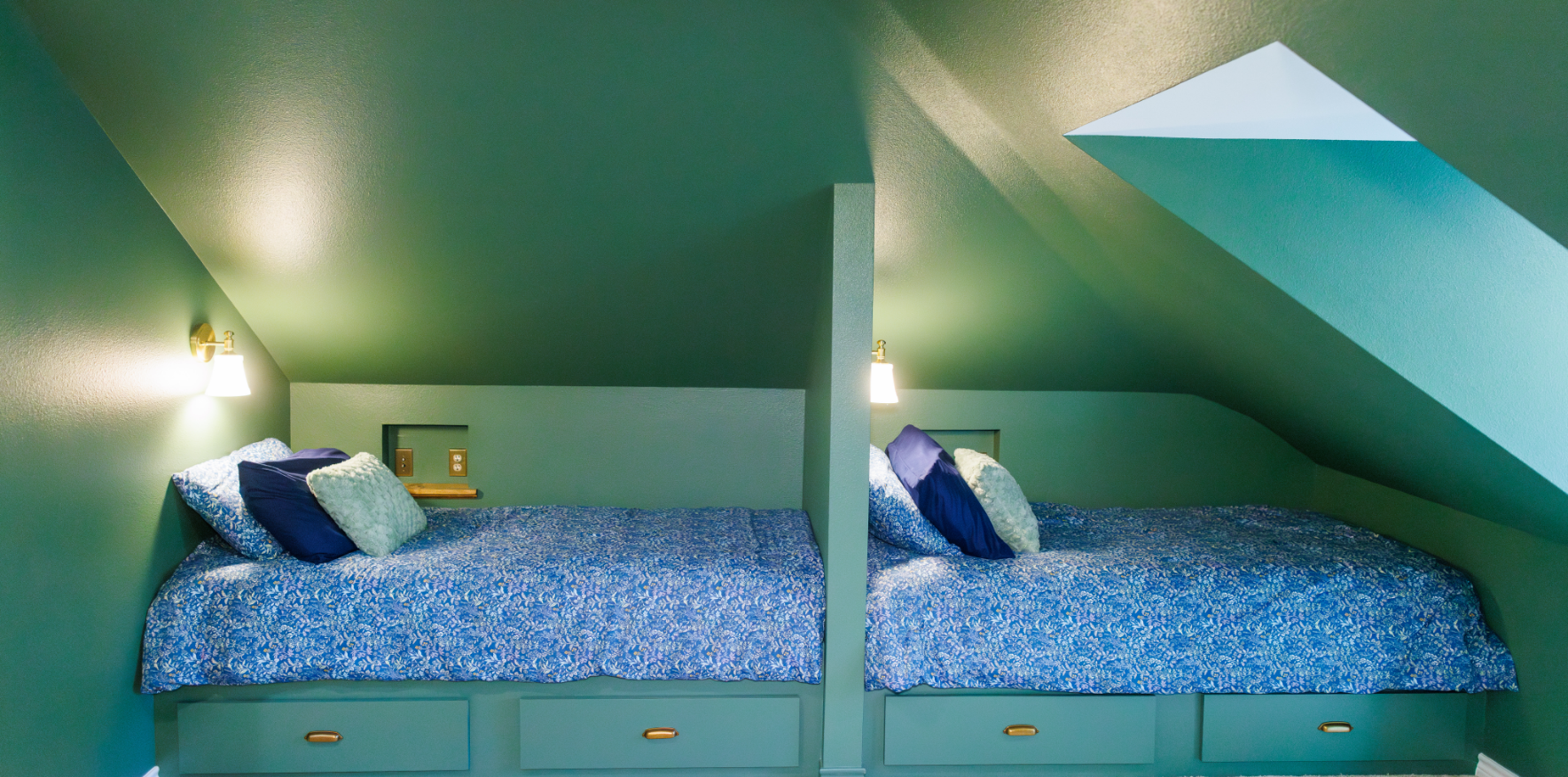 A couch with pillows in front of a kitchen with chairs.